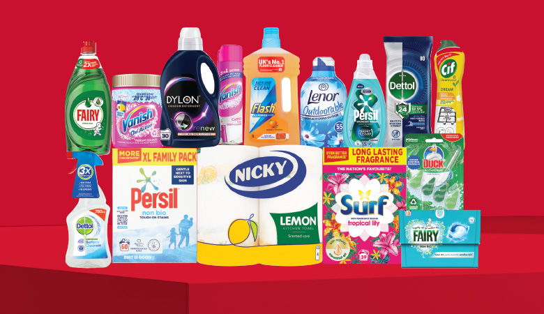 A promotional image showcasing various household cleaning and laundry products against a red backdrop. Featured brands include Fairy, Vanish, Dylon, Flash, Lenor, Dettol, Persil, Cif, Nicky, Surf, and Duck.