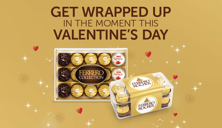 The image features a golden background with two Ferrero chocolate gift boxes, one labeled "Ferrero Collection" and the other "Ferrero Rocher." The text reads, "Get wrapped up in the moment this Valentine's Day," accompanied by small decorative hearts and sparkles.