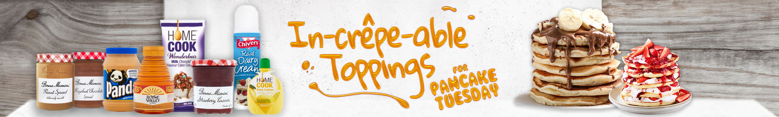 A banner with the playful text "In-crêpe-able Toppings for Pancake Tuesday" in a dripping, yellow font. Below, a variety of food items are displayed: Bonne Maman Peach Spread, Bonne Maman Fig Spread, Panda Peanut Butter, Bonne Maman Strawberry Jam, a can of Elvine Valley Maple Syrup, a box of Home Cook Wonderbar Milk Chocolate, a spray can of Chivers Real Dairy Cream, and a bottle of Home Cook Orange Juice. In the center, a stack of pancakes is shown, with one topped with bananas and chocolate sauce, and another with strawberries and cream. This banner promotes delicious topping options for Pancake Tuesday