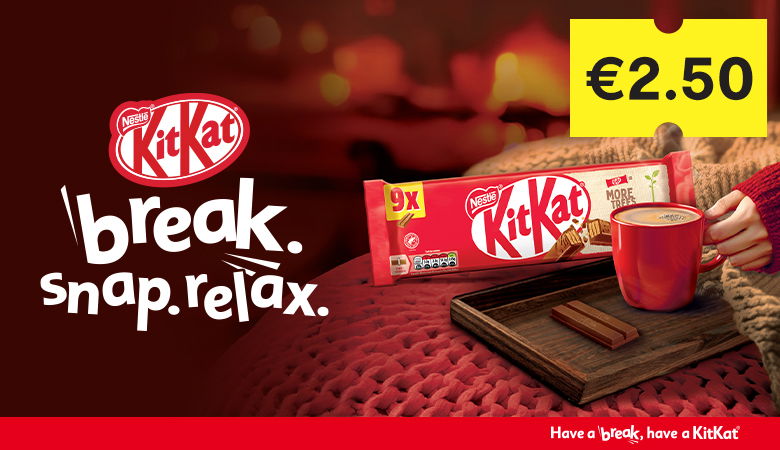 The image is a cozy ad for Nestlé Kit Kat, featuring a 9-pack of Kit Kat bars on a wooden tray with a steaming red mug and an unwrapped bar. The tagline "break. snap. relax." appears on the left, and the price (€2.50) is displayed on a bright yellow tag. A red banner at the bottom reads, "Have a break, have a Kit Kat." Warm lighting and soft textures create a comforting atmosphere.