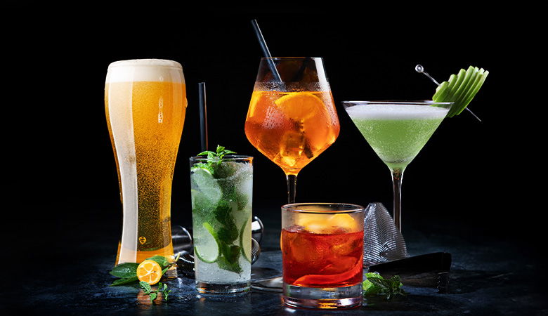 A selection of different shape glasses filled with beer and cocktails, with alochol and without alochol