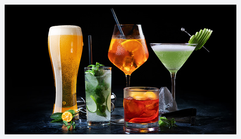 A selection of different shape glasses filled with beer and cocktails, with alochol and without alochol