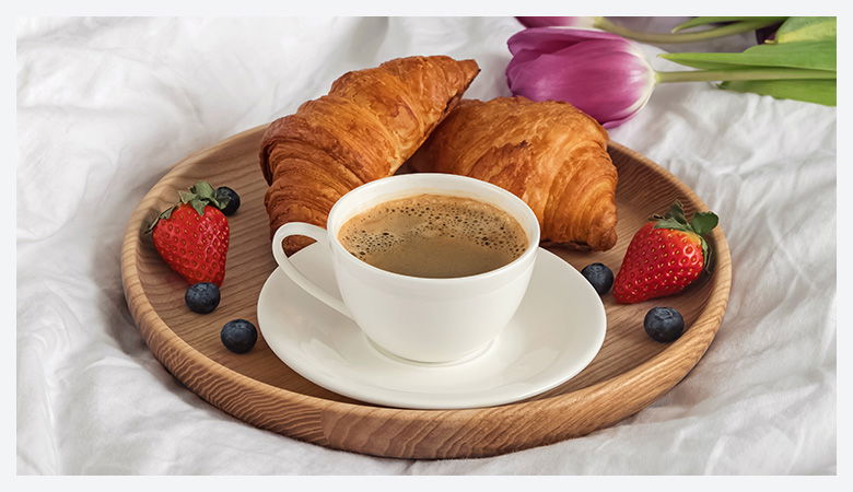A breakfast table, with a selectio of breakfast treats, like sausages, pancakes, croissants